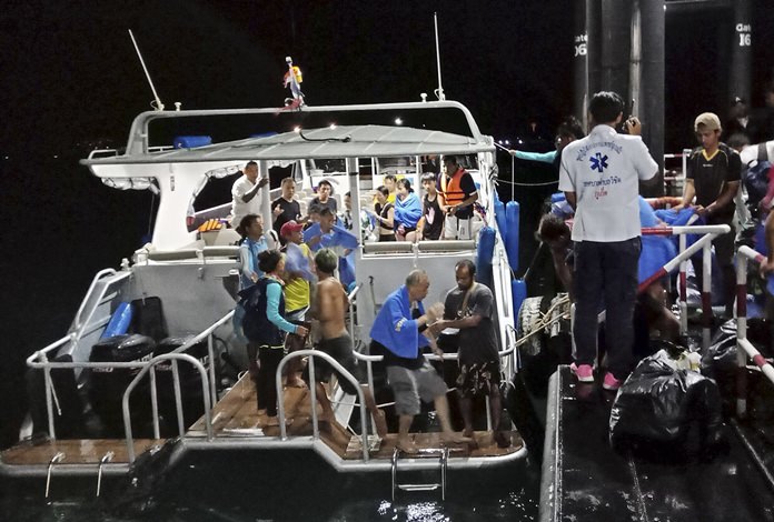 Rescued tourists from a boat that sank are helped onto a pier Thursday, July 5, on the island of Phuket. (Thailand Royal Police via AP)