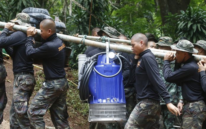 Soldiers carry a pump to help drain the rising flood water in a cave where 12 boys and their soccer coach were trapped since June 23. (AP Photo/Sakchai Lalit)