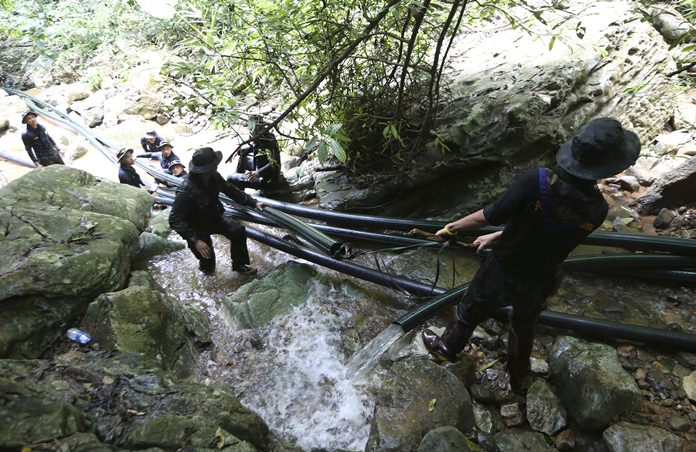 Thai soldiers drag pipes to divert mountain runoff water away from the cave where 12 boys and their soccer coach were trapped since June 23. (AP Photo/Sakchai Lalit)