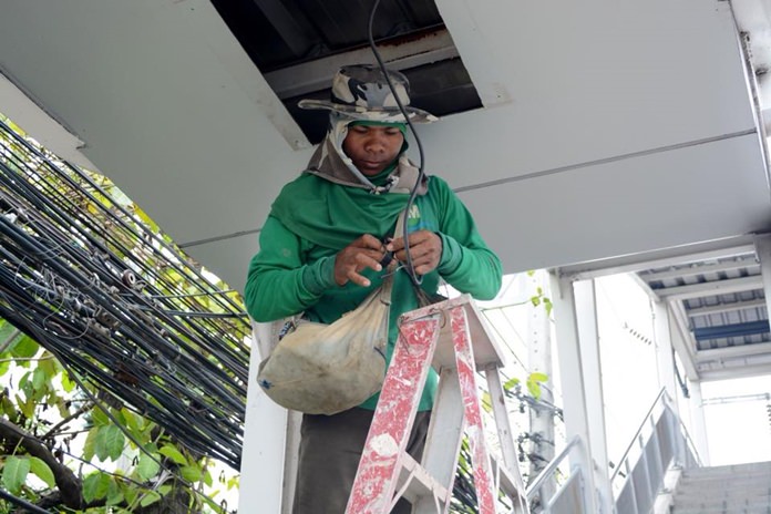 A city electrician works on tidying up wires after Pattaya officials insisted the pedestrian overpass near School No. 5 was safe, despite a report that a 10-year-old boy suffered a serious electric shock when he touched a steel handrail.