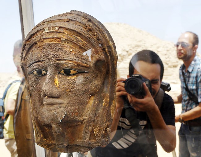 A photographer films a gilded silver mummy mask found on the face of the mummy of the second priest of Mut, as it is displayed during a press conference in front of the step pyramid of Saqqara, in Giza, Saturday, July 14, 2018. Archaeologists say they have discovered a mummification workshop dating back some 2,500 years at an ancient necropolis near Egypt’s famed pyramids. (AP Photo/Amr Nabil)