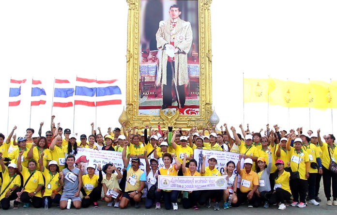 Runners and walkers pose in front of a photo of His Majesty the King on Pattaya Beach Road, Saturday, July 14, after completing a charity walk-run for the family of Navy SEAL Saman Kunan 