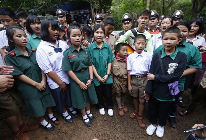 Friends sing a song outside of a cave complex where 12 boys and their soccer coach are trapped inside, in Mae Sai, Chiang Rai province, in northern Thailand, Wednesday, July 4, 2018. The Thai soccer teammates stranded more than a week in the partly flooded cave said they were healthy on a video released Wednesday. (AP Photo/Sakchai Lalit)