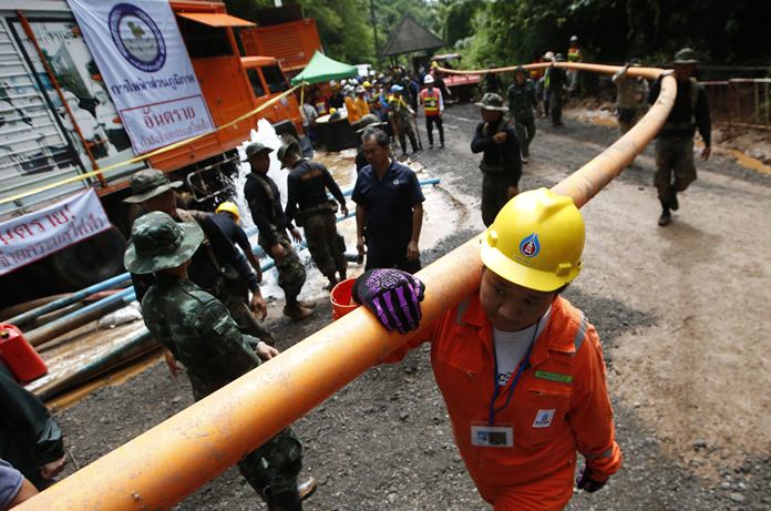 Rescuer carrying water pipe makes their way up at the entrance to a cave complex where 12 boys and their soccer coach were trapped inside when heavy rains flooded the cave, in Mae Sai, Chiang Rai province, in northern Thailand, Wednesday, July 4, 2018. Heavy rains forecast for later this week could complicate plans to safely extract them. (AP Photo/Sakchai Lalit)