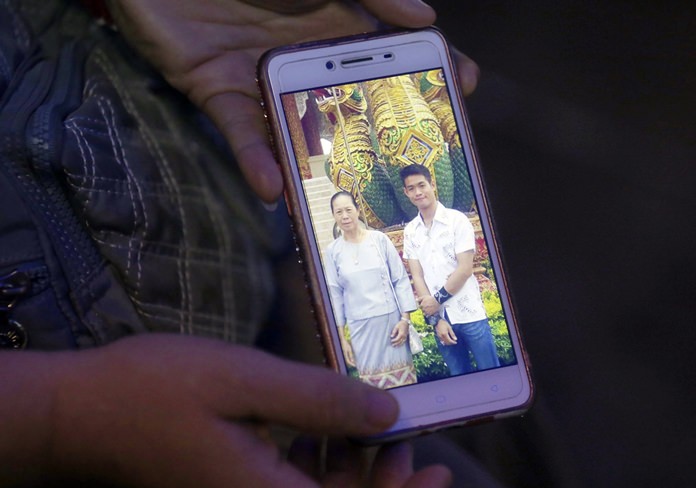 The aunt of coach Ekapol Chantawong shows a picture of the coach and his grandmother on a mobile phone screen, in Mae Sai, Chiang Rai province, in northern Thailand, Wednesday, July 4, 2018. (AP Photo/Sakchai Lalit)
