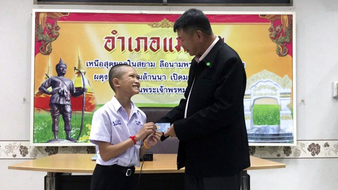 Mongkol Boonpiam, left, one of the young soccer players who had been trapped for almost three weeks in a cave in northern Thailand, receives an identity card denoting Thai citizenship from Somsak Kunkam Sheriff of Mae Sai during a ceremony in Mae Sai district, Chiang Rai province, Wednesday, Aug. 8. (Chiang Rai Public Relations Office via AP)