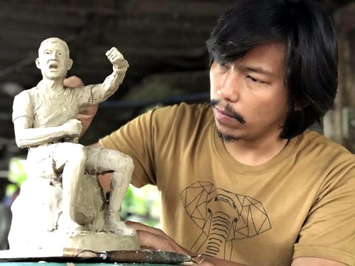 Artist Krisana Napulphol holds a sculpture of former Thai Navy SEAL Saman Kunan at his studio in Nakhon Pathom.