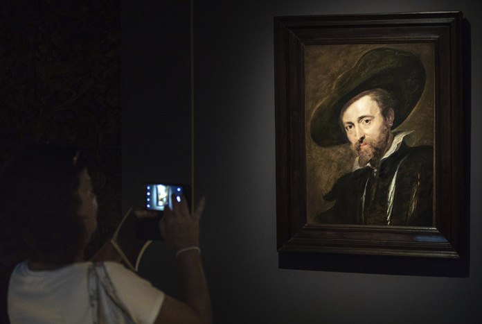 In this photo taken on Thursday, July 26, 2018, a visitor looks at the restored Peter Paul Rubens self-portrait from 1628 in the Rubenshouse in Antwerp, Belgium. (AP Photo/Olivier Matthys)