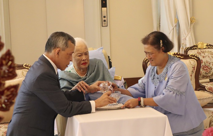 Her Majesty Queen Sirikit together with HM King Maha Vajiralongkorn and HRH Princess Maha Chakri Sirindhorn make merit by pouring holy water into a bowl. (The Royal Household Bureau via AP)