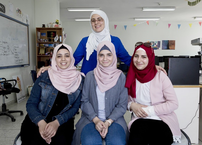 In this Thursday, Aug. 2, 2018 photo, Tamara Awaysa, 17, left, Wassan al-Sayyed, 17, center and Massa Halawa, 16, right, pose for a photo with their mentor Yamama Shakaa in the West Bank city of Nablus. The four Palestinian high school friends made it to the finals of a worldwide app competition among more than 19,000 teens. (AP Photo/Nasser Nasser)