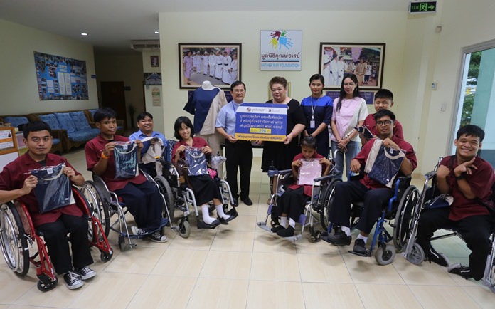 Hospital business development director Jutaporn Huyakorn presents specially tailored shirts, which students can put on and remove themselves, to Father Ray Foundation Vice President Rev. Michael Picharn Jaiseri at the Redemptorist School for Persons with Disabilities.