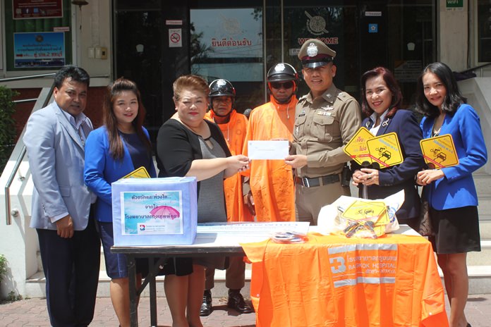 Business development director Jutaporn Huyakorn presents 30 raincoats to officers at Banglamung Police Station for them to use during the rainy season.