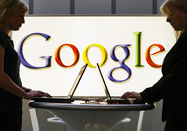 In this April 17, 2007, file photo exhibitors of the Google company work in front of an illuminated sign at the industrial fair Hannover Messe in Hanover, Germany. (AP Photo/Jens Meyer, File)