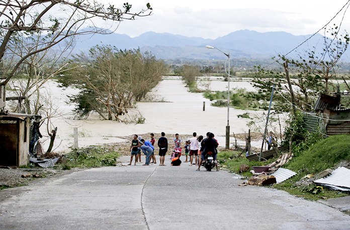 In this Saturday, Sept. 15, 2018, photo, residents stand by a flooded road following the onslaught of Typhoon Mangkhut in Tuguegarao City in Cagayan province, northeastern Philippines. (AP Photo/Aaron Favila, File)