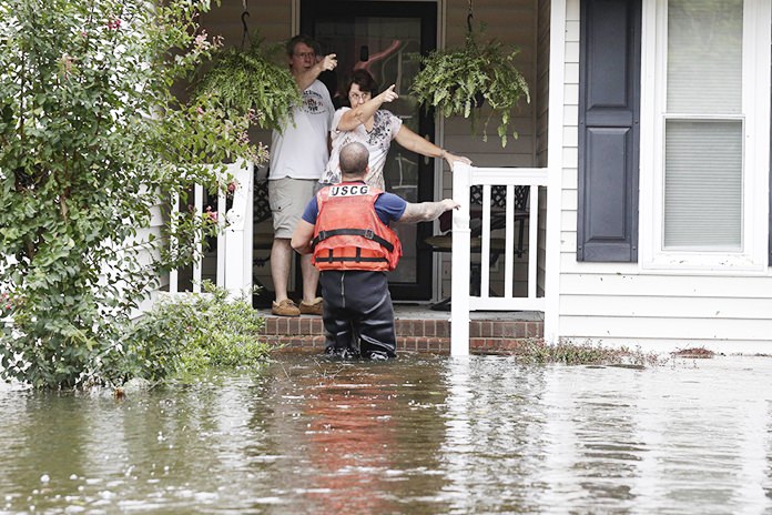 A member of the U.S. Coast Guard assists Roger and Susan Hedgepeth in Lumberton, N.C., Sunday, Sept. 16, following flooding from Hurricane Florence. (AP Photo/Gerry Broome)