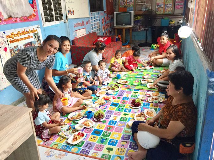 Kantana Pornchai, director of the center, and community helpers serve lunch to the children.