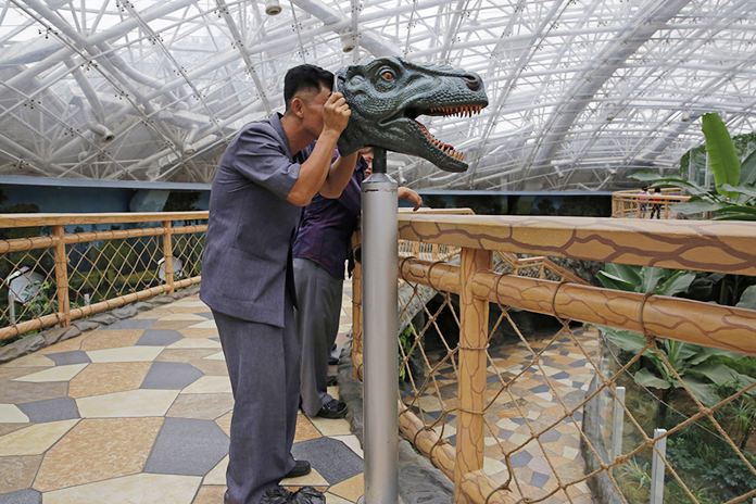 A North Korean man looks through a device to study the vision of a dinosaur, at the Central Zoo in Pyongyang, North Korea. (AP Photo/Kin Cheung, File)