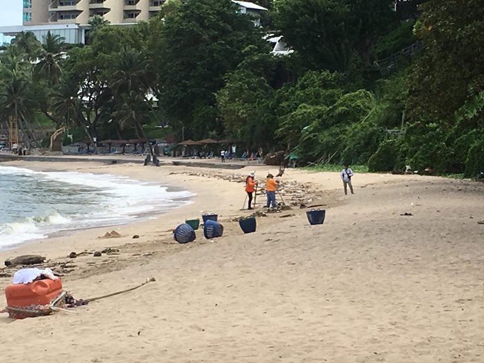 Pattaya sanitation workers clean up Yim Yom Beach after a heavy storm dumped waves of garbage.