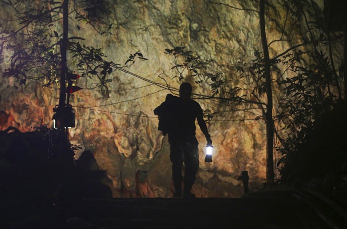 In this Wednesday, July 4, 2018, file photo, a rescuer makes his way down the entrance to the cave complex where 12 boys and their soccer coach went missing in Mae Sai, Chiang Rai province, northern Thailand. (AP Photo/Sakchai Lali)