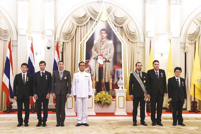 From left, Japanese cave diver Shigeki Miyake, Belgian cave diver Ben Reymenants, American cave diver Joshua David Morris, Thai Prime Minister Prayuth Chan-ocha, Finnish cave diver Mikko Paasi, American cave diver Bruce Konefe and Japanese cave diver Shigeki Miyake pose in front of an image of His Majesty King Maha Vajiralongkorn at the Royal Decoration Ceremony for aiding the rescue of the Wild Boars soccer team trapped for almost three weeks in a flooded cave, at the Royal Thai Government House in Bangkok Friday, Sept. 7, 2018. (Lillian Suwanrumpha/Pool Photo via AP)