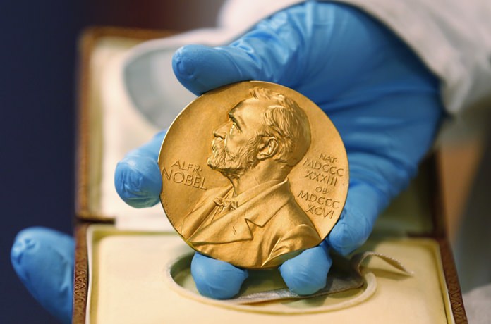 In this file photo dated Friday, April 17, 2015, a national library employee shows the gold Nobel Prize medal awarded to the late novelist Gabriel Garcia Marquez, in Bogota, Colombia. (AP Photo/Fernando Vergara)