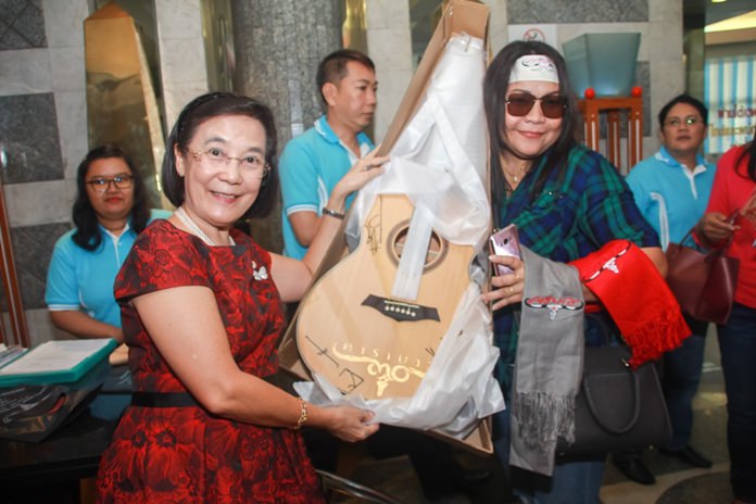 Local HHNFT Director Radchada Chomjinda presents a guitar signed by members of the Carabao band to the lucky auction winner, whose winning bid of 4,000 baht will go towards helping the orphans.