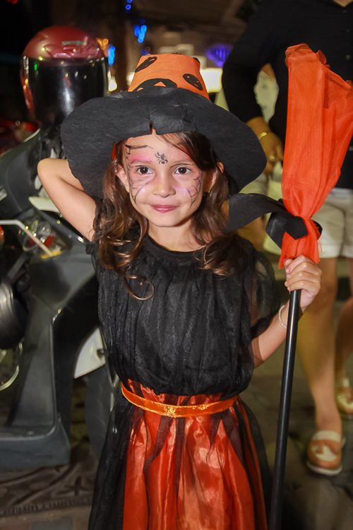 A little witch pauses for some candy before taking off on her broom.