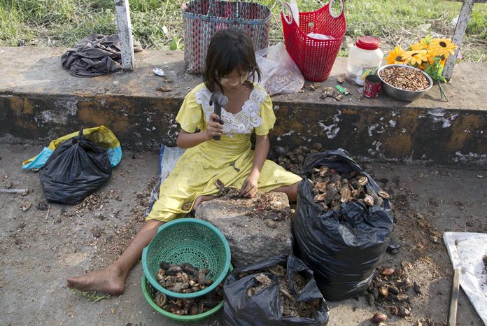 A girl uses a hammer to crack open shells for edible seeds to sell as snacks in Yangon, Myanmar. (AP Photo/Thein Zaw 18/11/1)