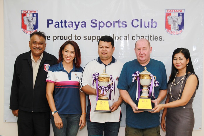 PSC darts team captain Rolly Gabiana (center) and Paul Cornwell, Social Chairman of the Pattaya Sports Club (2nd right) hold the Singles and Team trophies from the 2018 PEA Darts Open, flanked by (from left) PSC President Peter Malhotra, PSC Acting Secretary & Publicity Manager Ingkarat Chaimongkon and PSC Charity Chairperson Noi Emmerson.