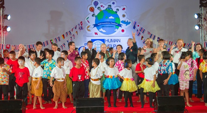 Happy benefactors and supporters together with the children wave the ‘love’ sign.