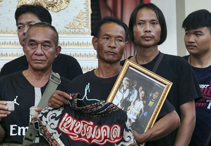 Relatives of 13-year-old Thai kickboxer Anucha Tasako hold his boxing shorts and a portrait during his funeral services in Samut Prakan province. Anucha died of a brain hemorrhage two days after he was knocked out in a bout on Nov. 10 that was his 174th match in the career he started at age 8. (AP Photo/Sakchai Lalit)