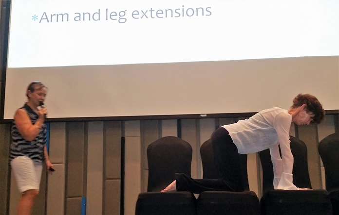 Diana Mountanos from Pure Yoga assists by performing several exercises as Gay Burnett from Surecell Medical describes them and their purpose in helping to alleviate or avoid back pain.