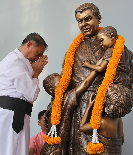 Father Peter lays a garland on the statue of Father Ray, the school’s founder.