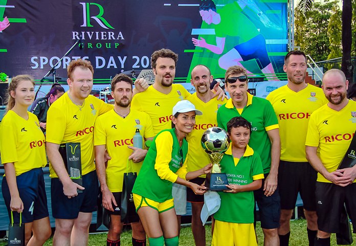 Winston and Sukanya Gale and their son Toby of the Riviera Group team (green shirts) present the football champions trophy to the victorious Regents School football squad during the Riviera Group Sports Day, November 24 at the Regents International School in Pattaya.