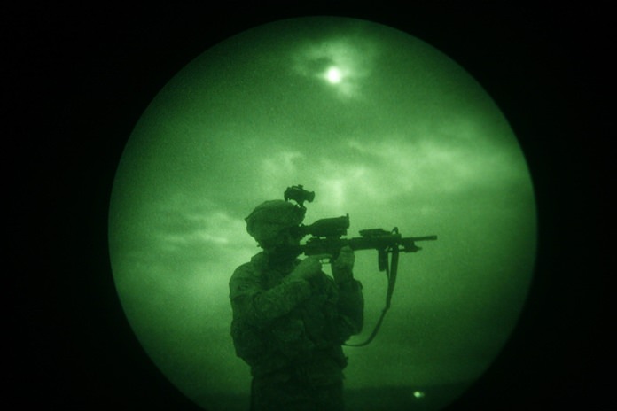 A U.S. soldier looks through the scope of his weapon during a night patrol in Mandozai, in Khost province, Afghanistan, seen through night vision equipment. About 400,000 veterans had a PTSD diagnosis in 2013, according to the Veterans Affairs health system. (AP Photo/Rafiq Maqbool)