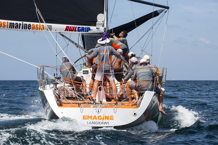 The crew on Emagine work hard to hoist a sail.