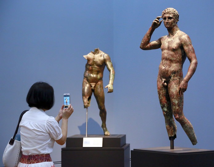 A woman takes a photo of a sculpture titled "Statue of a Victorious Youth, 300-100 B.C." at the J. Paul Getty Museum in Los Angeles. (AP Photo/Nick Ut)