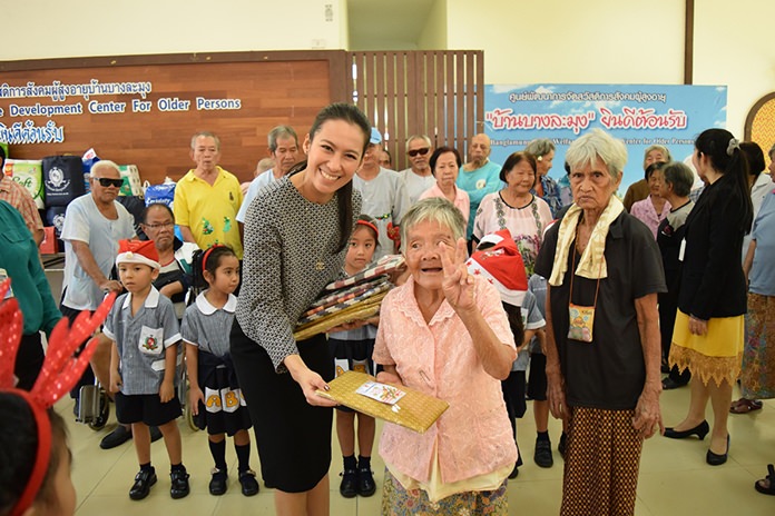Satit School Director Ms. Titipun Pettrakul handing out early Christmas gifts to the elderly.