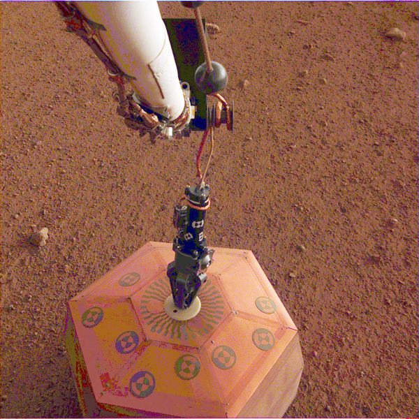 This photo provided by NASA Jet Propulsion Laboratory shows the new Mars lander placing a quake monitor on the planet’s dusty red surface. (NASA Jet Propulsion Laboratory via AP)