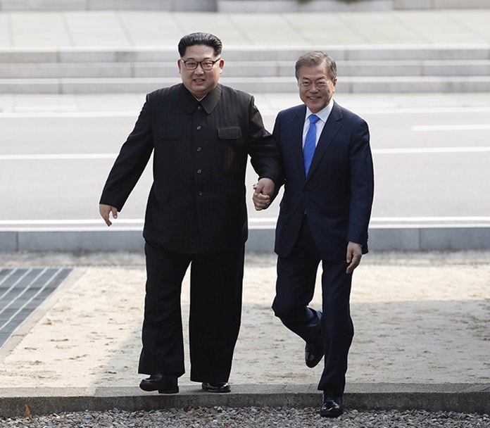 North Korean leader Kim Jong Un, left, and South Korean President Moon Jae-in, right, cross the military demarcation line to the South side at the border village of Panmunjom in the Demilitarized Zone, South Korea, on April 27, 2018. (Korea Summit Press Pool via AP)