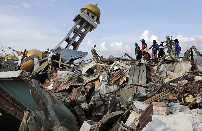 Rescuers and villagers wait for news for their missing loved ones as recovery efforts continue after liquefaction hit the neighborhood of Balaroa in Palu, Central Sulawesi, Indonesia, on Oct. 6, 2018. (AP Photo/Aaron Favila)