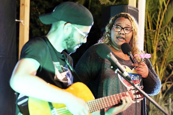 In this Jan. 12, 2019 photo, Venezuelan singer Reymar Perdomo performs with fellow Venezuelan and guitarist Omar Rumbos at a fair on the beach of San Bartolo, Peru. (AP Photo/Martin Mejia)