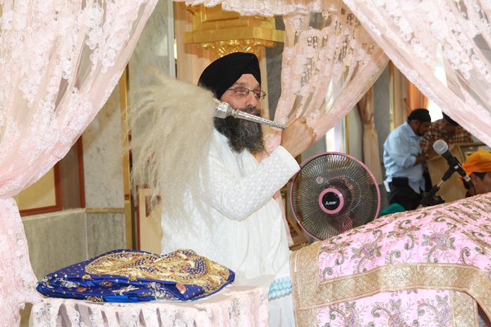 Gianiji Deep Singh waves the Chaur Sahib (ceremonial whisk) over the sacred Guru Granth Sahib.