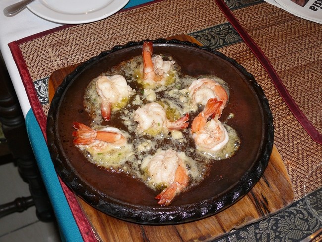 The garlic prawns cooked in butter with chopped garlic come on a sizzling plate.