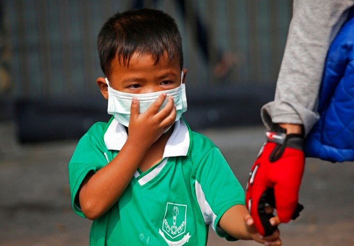 A young boy wears a protective mask for the high levels of air pollution as he's picked up from school in Bangkok, Wednesday, Jan. 30. (AP Photo/Sakchai Lalit)