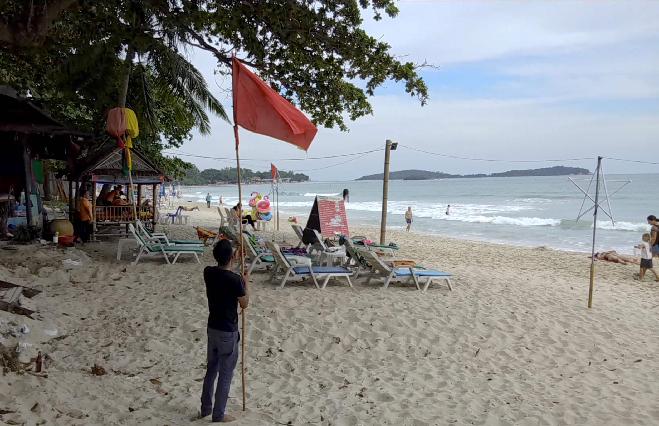 A man raises a red flag indicating rough weather conditions in Chaweng beach, Koh Samui, Thailand, Thursday, Jan. 3. (AP Photo/Sithipong Charoenjai)