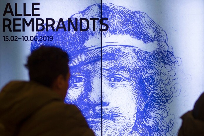A visitor passes a billboard drawing attention to the exhibit of all the Rijksmuseum’s Rembrandts in Amsterdam, Netherlands, Wednesday, Feb. 13. (AP Photo/Peter Dejong)