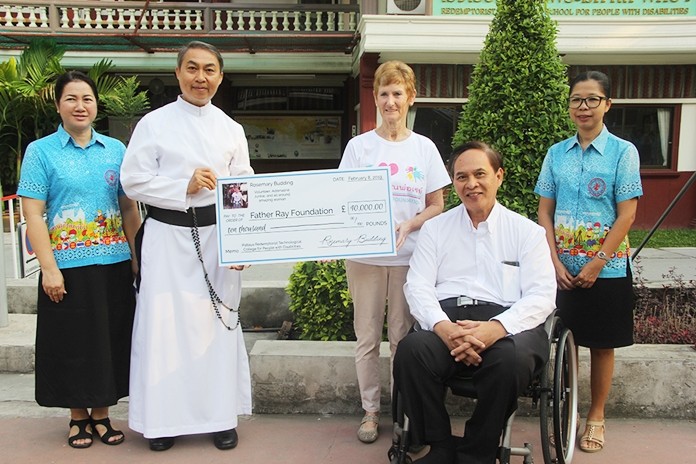 Rosemary Budding presents the cheque to Father Peter, President of the School for People with Disabilities.