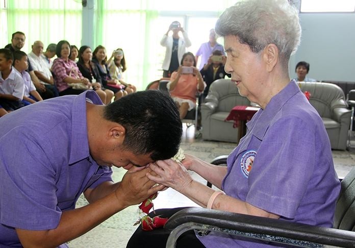 Khun Aurora received a garland from the new head teacher on her retirement.