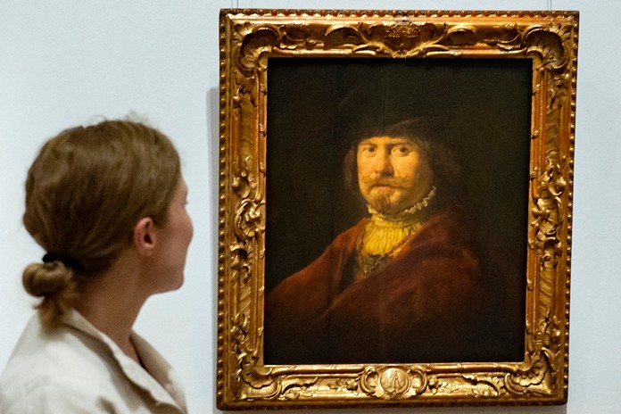 A woman stands in front of the painting 'Rembrandt in a red coat' (c. 1644) by Govaert Flinck during a press preview of the exhibition 'Rembrandt's Mark' in Dresden, eastern Germany, Thursday, June 13, 2019. (AP Photo/Jens Meyer)